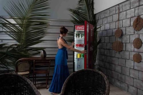 una mujer parada frente a un refrigerador abierto en Reserva do Paiva suites, en Cabo de Santo Agostinho