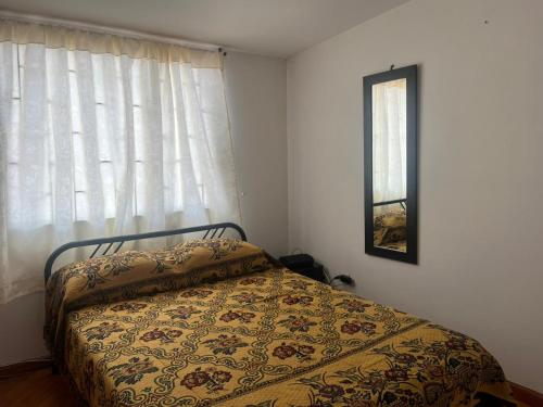 um quarto com uma cama e uma janela com um cobertor em Bhospedaje em Manizales