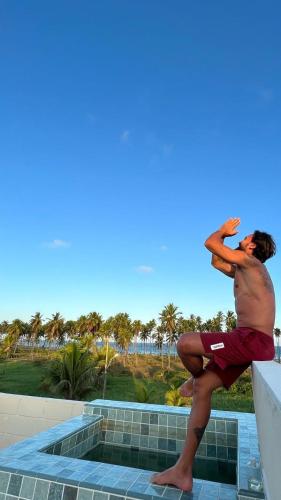 a man sitting on the ledge of a swimming pool at Reserva do Paiva suites in Cabo de Santo Agostinho
