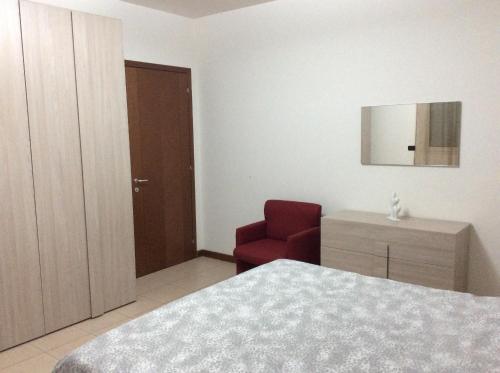 a bedroom with a bed and a red chair at La Casa di Lorella in Terni