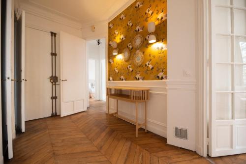 a hallway with a table and a wall with plates at Residence Gustave Eiffel - PARIS in Paris
