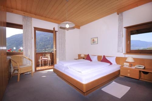 Schlafzimmer mit einem Bett, einem Schreibtisch und Fenstern in der Unterkunft Apartments Gasserhof in Algund