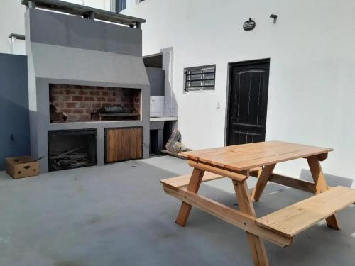 una mesa de picnic de madera en una habitación con chimenea en soma departamentos en Las Toninas