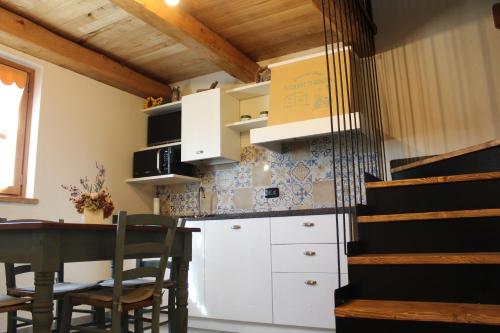 uma cozinha com armários brancos e uma mesa com cadeiras em 'L ciabot 'd Ginota em Barge