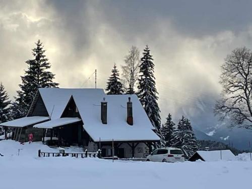 una casa cubierta de nieve frente a los árboles en La grande garde, en Les Avants