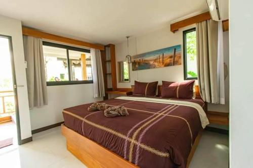 a bedroom with a large bed with two shoes on it at BangPo Resort in Ban Bang Po