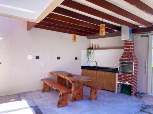 a kitchen with a wooden table and a sink at A 500m da PRAIA de Taperapuan, 2 quartos, até 6 pessoas, WiFi 300mbs, Churrasqueira, Chuveirão, Smart TV, Estacionamento Gratuito in Porto Seguro