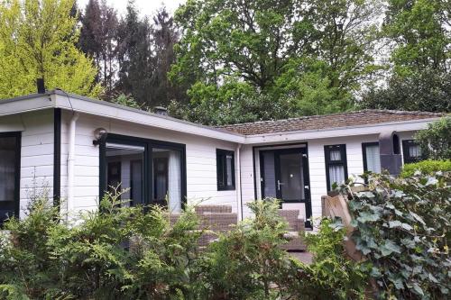 a white house with black windows and trees at Chalet Forest Putten even lekker weg. in Putten