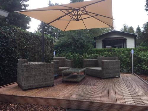 a patio with chairs and an umbrella on a deck at Chalet Forest Putten even lekker weg. in Putten