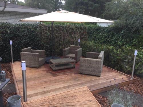 a patio with two chairs and an umbrella at Chalet Forest Putten even lekker weg. in Putten