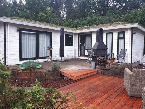 a backyard with a deck with a fireplace and a house at Chalet Forest Putten even lekker weg. in Putten