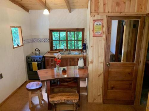 a kitchen with a wooden table and a wooden door at Cabaña entre Boldos in Villarrica