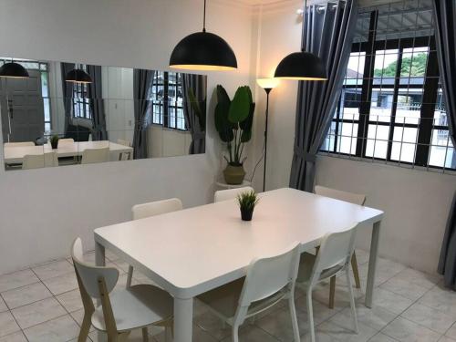 una mesa blanca y sillas en una habitación con ventanas en Dahlia Homestay (Wi-Fi & Netflix), en Miri