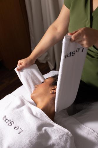 a woman laying on a bed with a towel on her face at Pullman Mazagan Royal Golf & Spa in El Jadida