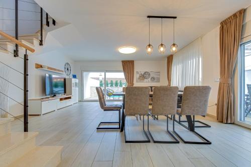 a dining room and living room with a table and chairs at Villa Insula in Linardići