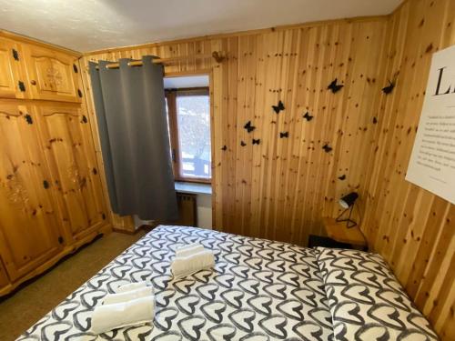 ein Schlafzimmer mit einem Bett in einem Zimmer mit Holzwänden in der Unterkunft Appartamento Valtournenche in Valtournenche