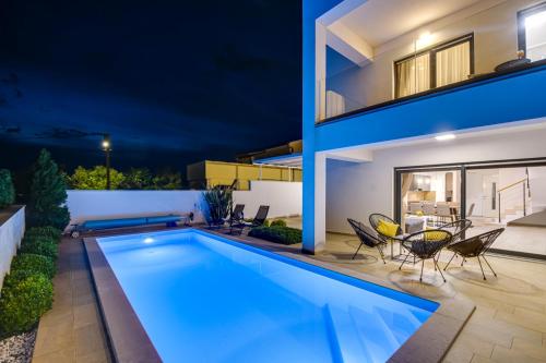 a swimming pool in the backyard of a house at night at Villa Insula in Linardići