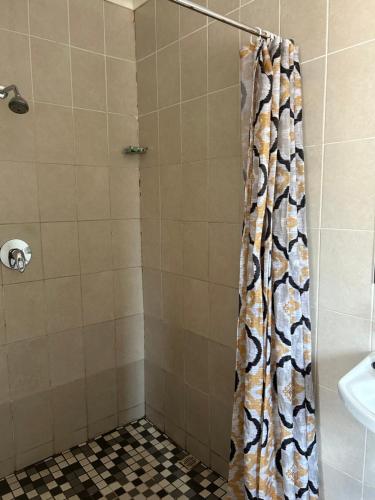 a shower with a shower curtain in a bathroom at Monica's Premium Guesthouse in Welkom