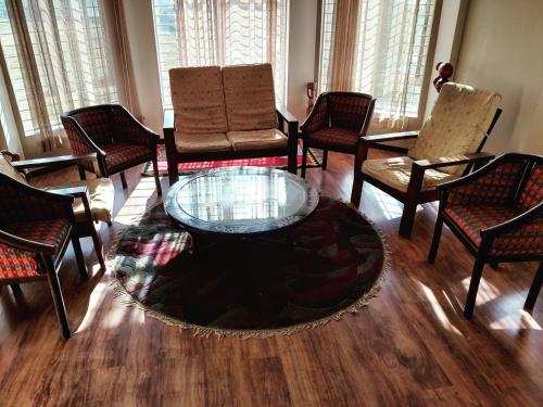 a living room with chairs and a glass table at Indrayanifarms in Sundarijal