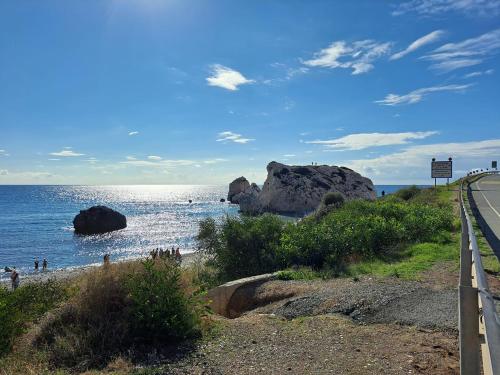 a beach with rocks in the water and a road at Chariandry Court in Pissouri