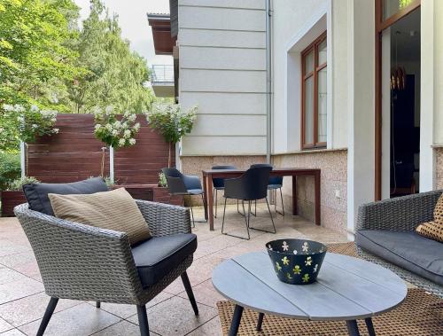 a patio with wicker chairs and a table and a fireplace at Apartament Relax Neptun Park in Gdańsk