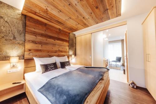 ein Schlafzimmer mit einem großen Bett und einer Holzwand in der Unterkunft Pension Linder in Seeboden