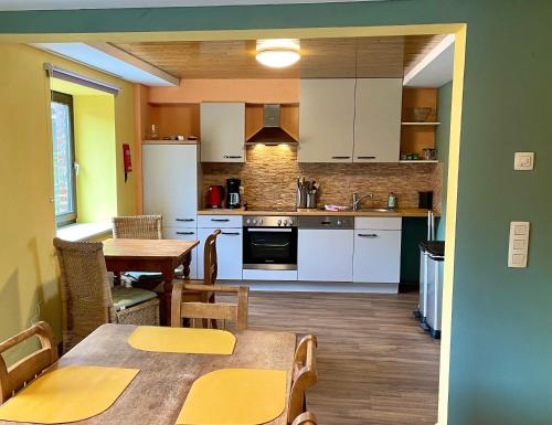 eine Küche mit weißen Schränken sowie einem Tisch und Stühlen in der Unterkunft Revival Ranch Ferienhaus in Büllingen