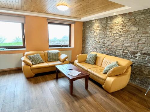 a waiting room with two couches and a stone wall at Revival Ranch Ferienhaus in Bullange