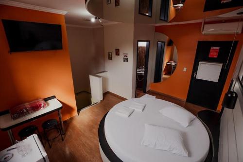 Kleines Zimmer mit einem weißen Bett und einem Tisch in der Unterkunft MOTEL MK 66 in Mairinque