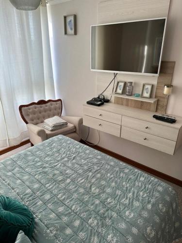 a bedroom with a bed and a tv and a chair at Departamento Papudo Laguna in Papudo