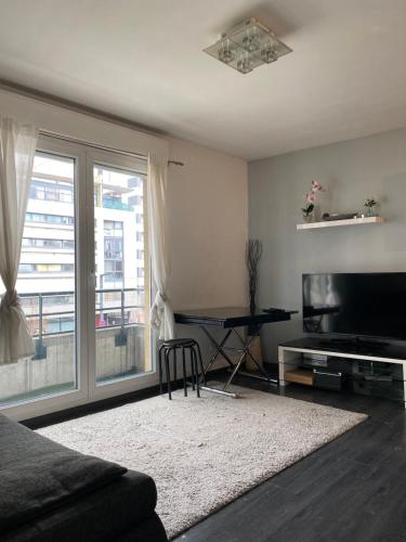 ein Wohnzimmer mit einem TV und einem Tisch in der Unterkunft Cosy Appt aux portes de Paris in Vitry-sur-Seine