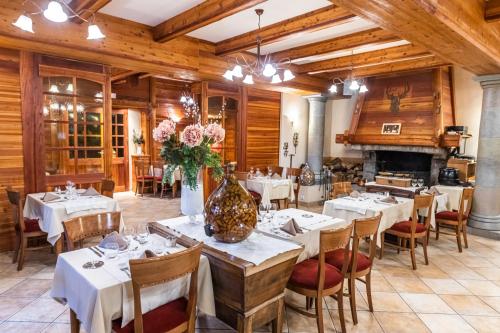 un restaurant avec des tables et des chaises blanches et une cheminée dans l'établissement Hotel-Restaurant Spa Les Peupliers, à Baratier