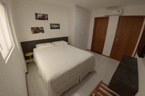 1 dormitorio con cama blanca y armario de madera en Apartamento Completo en Maceió