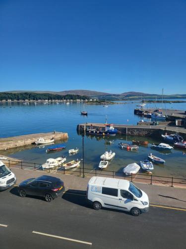 a group of cars parked next to a marina with boats at Wee Harbour View in Millport