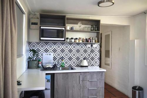 een keuken met een spoelbak en een magnetron bij Courtyard Studio lights and wi fi during load shedding in Stellenbosch