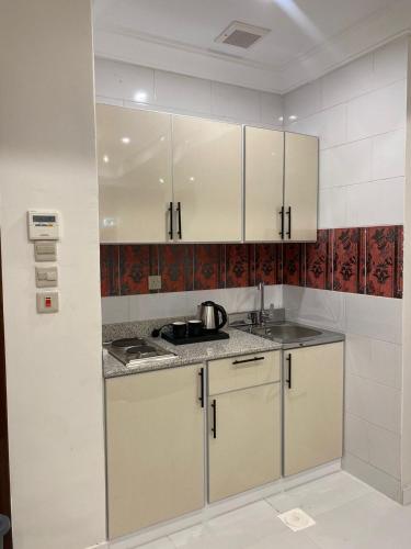 a kitchen with white cabinets and a sink at بولاريس للشقق المخدومه in Ar Ruʼays