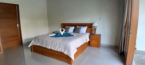 a bedroom with a large bed with a wooden frame at Umah Landuh in Ubud