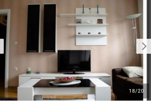 ein Wohnzimmer mit einem TV und einem weißen Couchtisch in der Unterkunft Andrea in Banja Luka