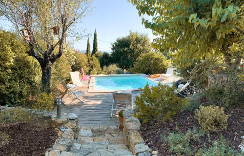 une piscine dans un jardin avec une terrasse en bois dans l'établissement Maset des Amandiers, à Cotignac
