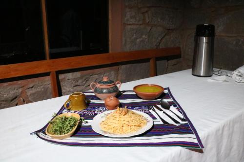 un tavolo con un piatto di pasta e verdure di BLUE SKY Lodge Taquile a Huillanopampa