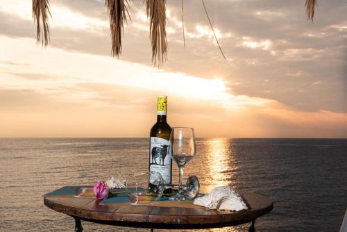 butelkę wina i kieliszek na stole w pobliżu oceanu w obiekcie Τraditional seaside room HOMER w mieście Artemida