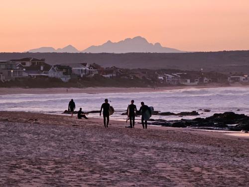 a group of people walking on the beach with surfboards at Point Villa in Jeffreys Bay