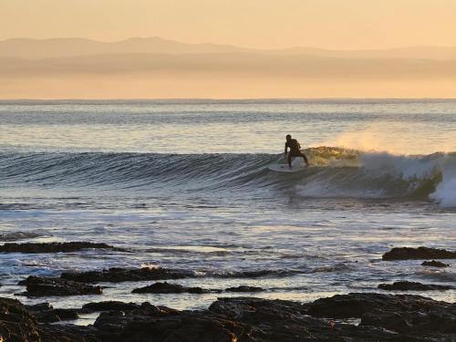 a man riding a wave on a surfboard in the ocean at Point Villa in Jeffreys Bay