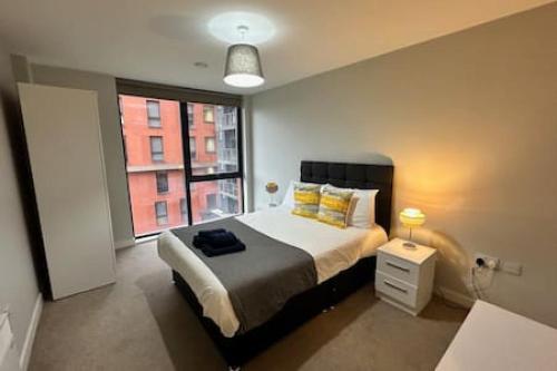 a bedroom with a large bed and a window at Fab 1 Bed Apartment with Balcony and River Views Sleeps 2 in Manchester