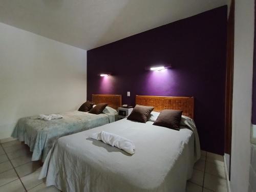 two beds in a room with purple walls at Los Ciruelos Oaxaca in Oaxaca City