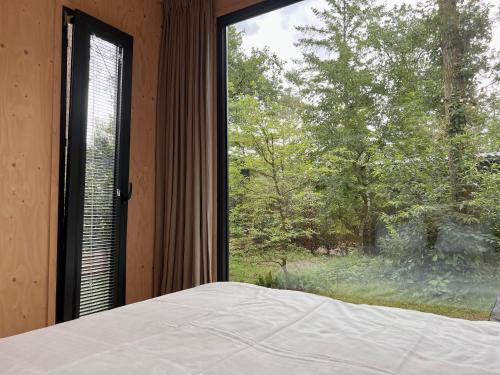 een slaapkamer met een bed en een groot raam bij Taiga tiny house in Nunspeet