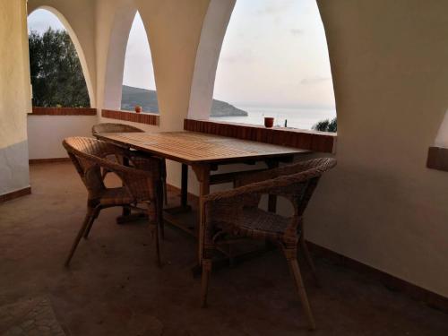 una mesa de madera y sillas en una habitación con ventanas en Villa Clementina - Sant'Antioco en SantʼAntìoco