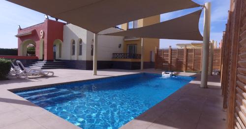 a swimming pool with an umbrella in front of a house at Utopia Villas - Ain Soukhna in Al Ḩafāʼir