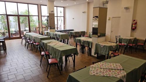 a dining room with green tables and chairs and windows at Hotel Cosmos in Mar del Plata