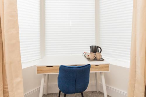 un escritorio con una silla azul junto a una ventana en Suite 1 - Lovely Ensuite in Oldham Sociable House en Oldham
